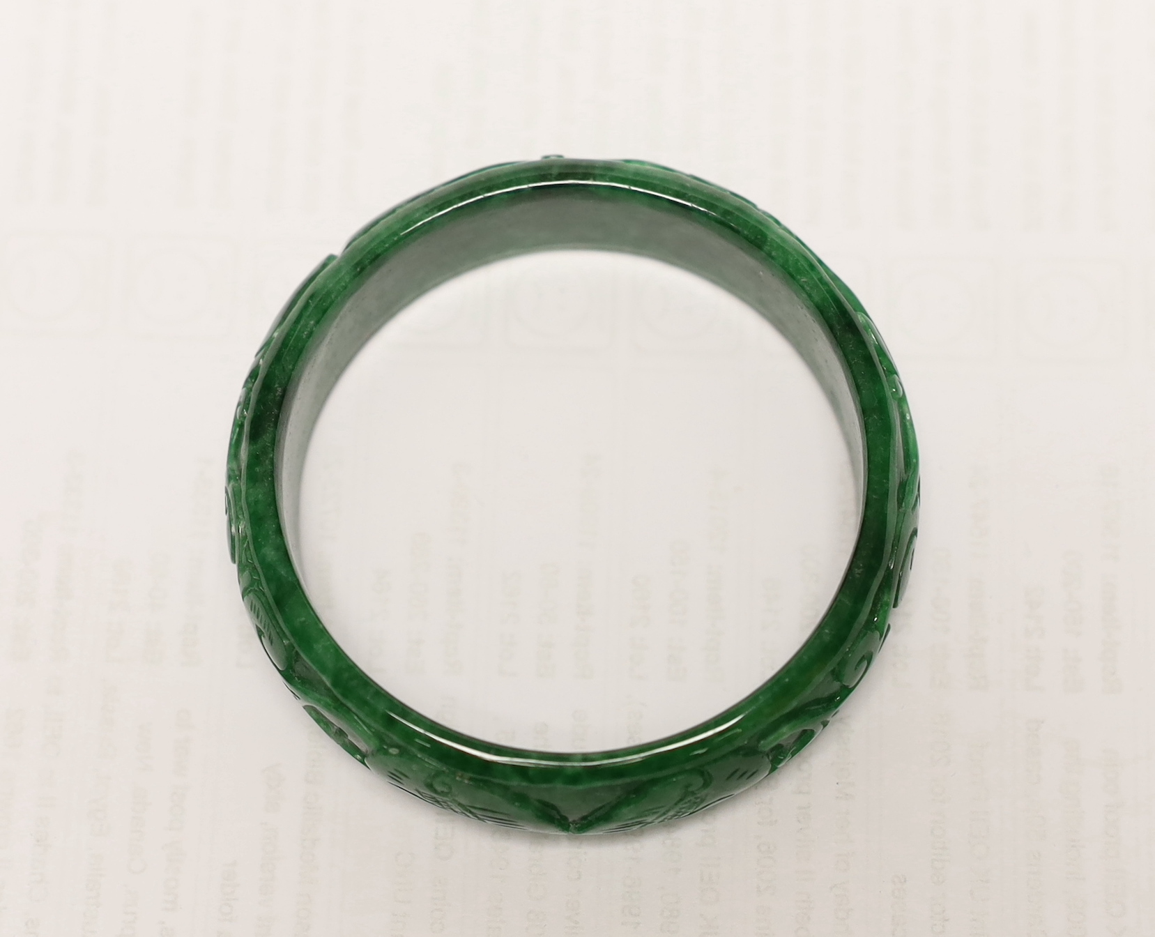 A Chinese carved jadeite bangle, 7.5cm in diameter